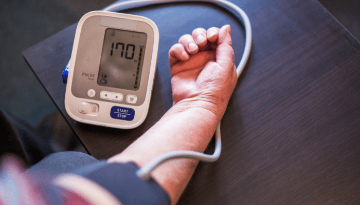 A person measuring blood pressure with a digital monitor at home