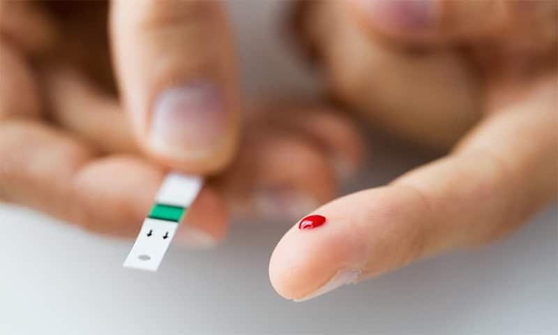 A person checking blood sugar with a glucometer