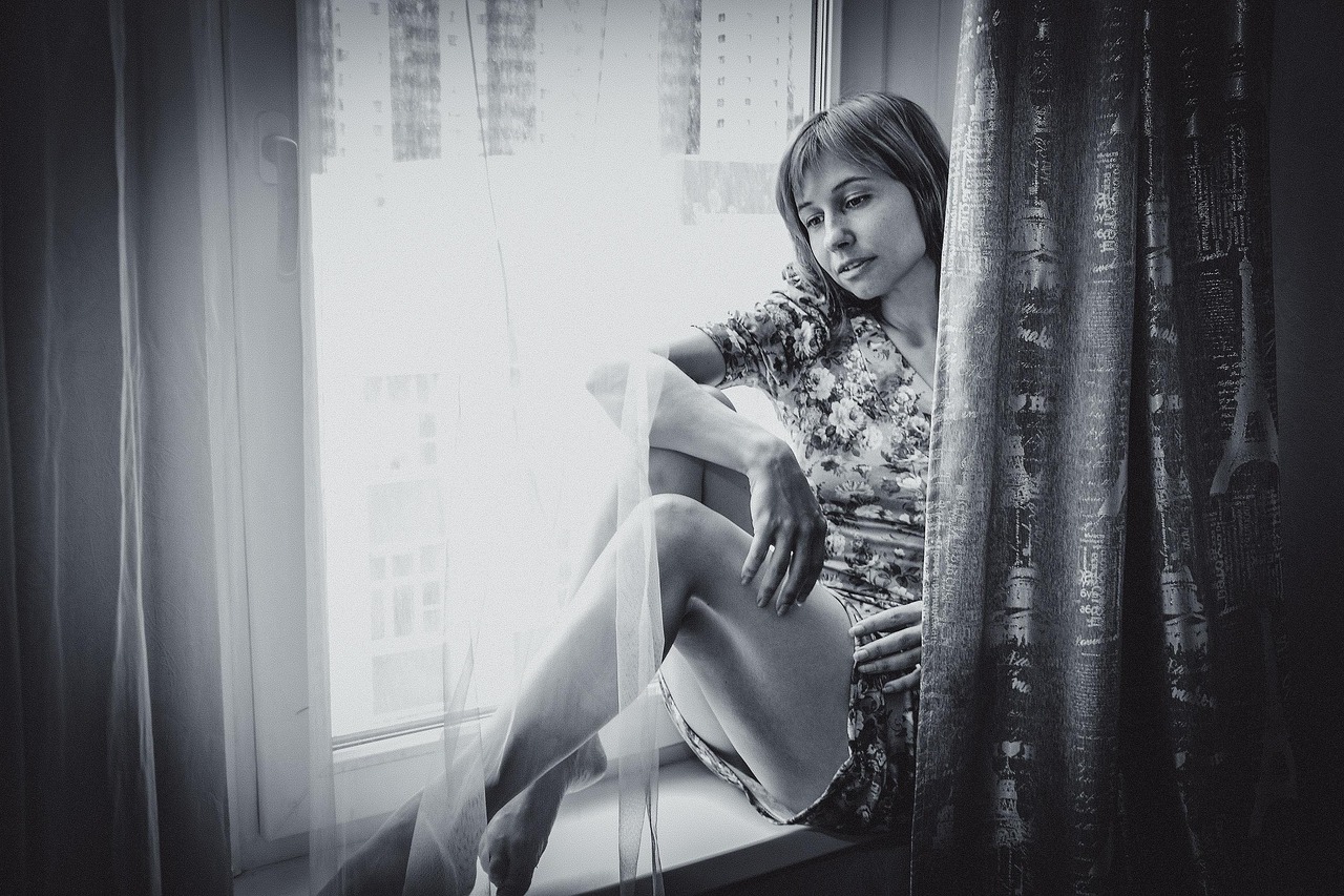 Woman sitting by a window, feeling low